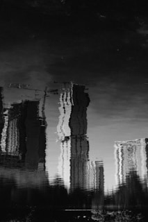 grayscale photo of reflection of buildings in water