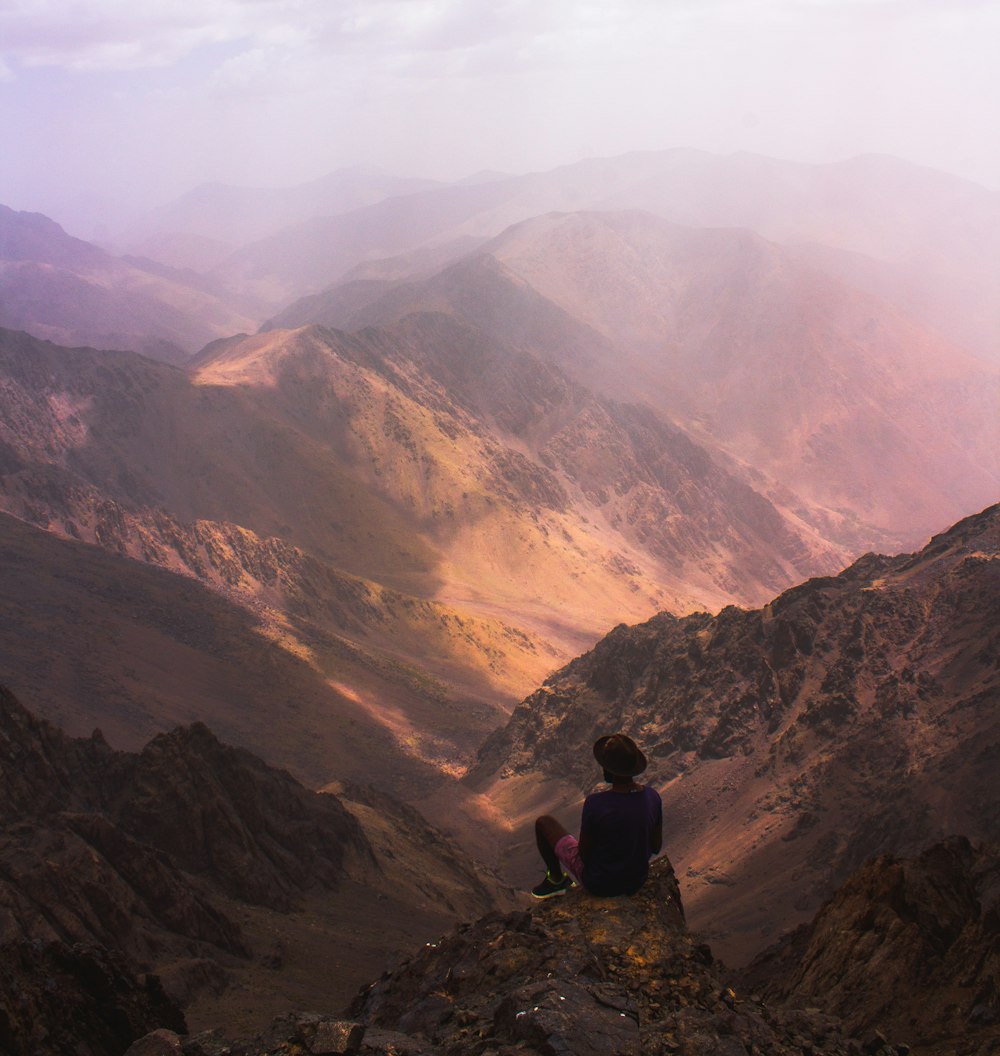 man sitting on mountain edge