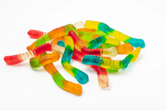 Close-up shot of translucent gummy worms glowing under soft light, inviting curiosity.