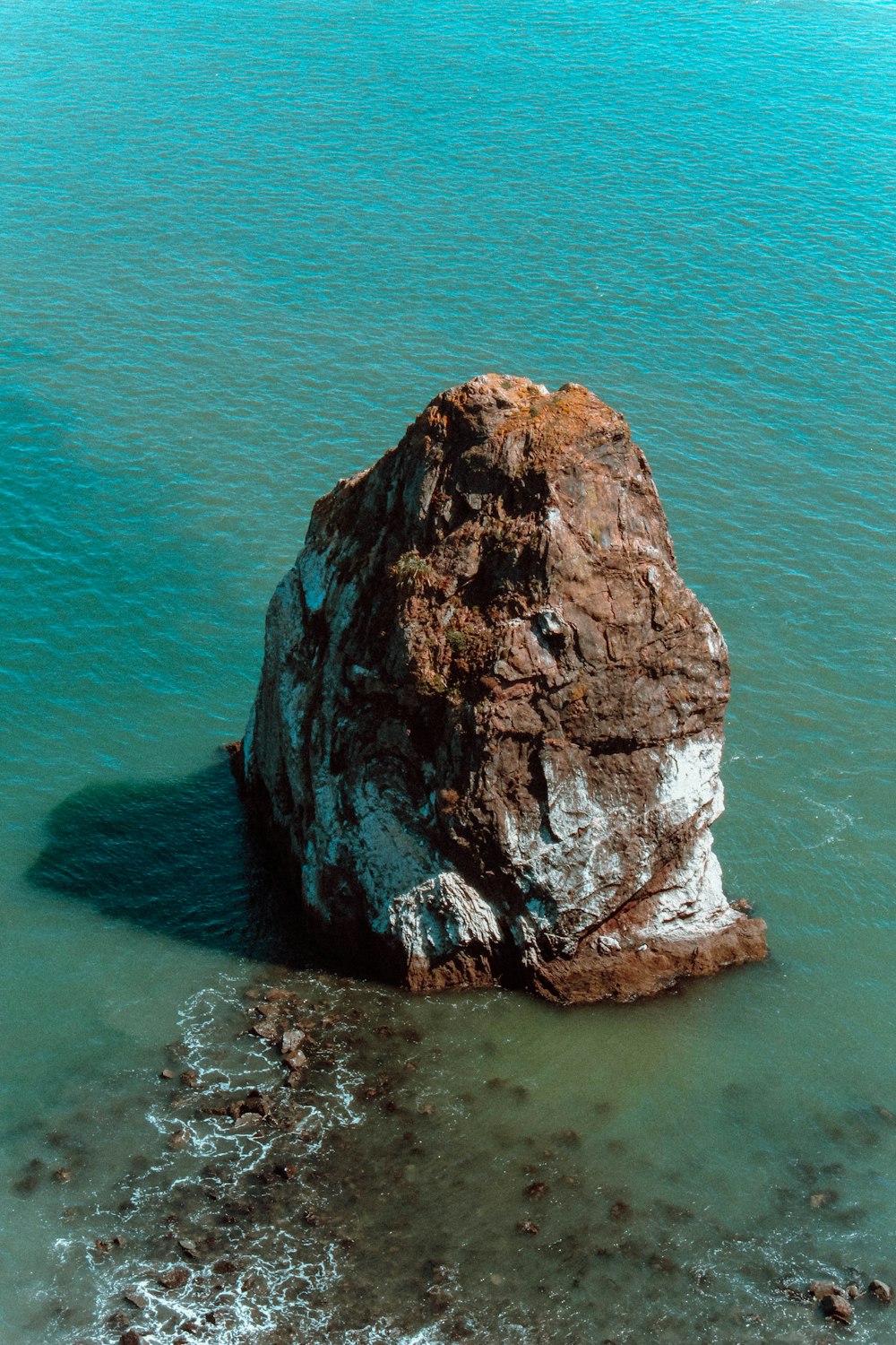 aerial photography of rock formation surrounded by body of water