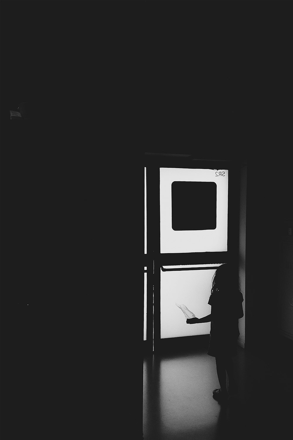 a black and white photo of a person standing in front of a door