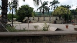 Peaceful courtyard area with stone benches and a small garden surrounded by green plants.
