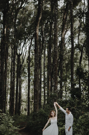 A joyful couple mid-dance under soft golden lighting, surrounded by lush sage green decor.