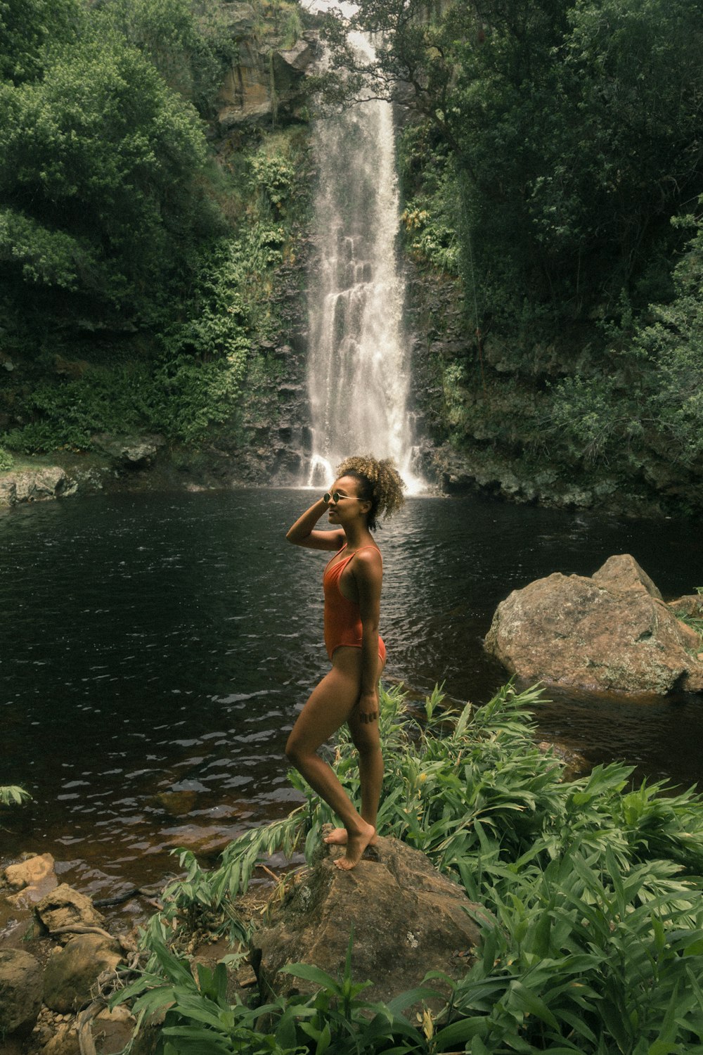 woman standing on rock formation near body of water