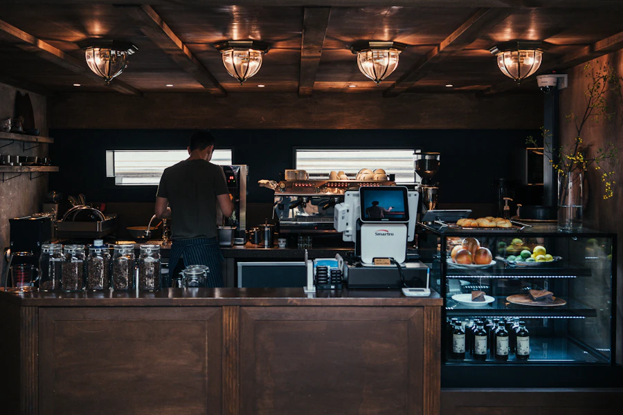 A barista at the espresso machine behind a warmly lit café counter