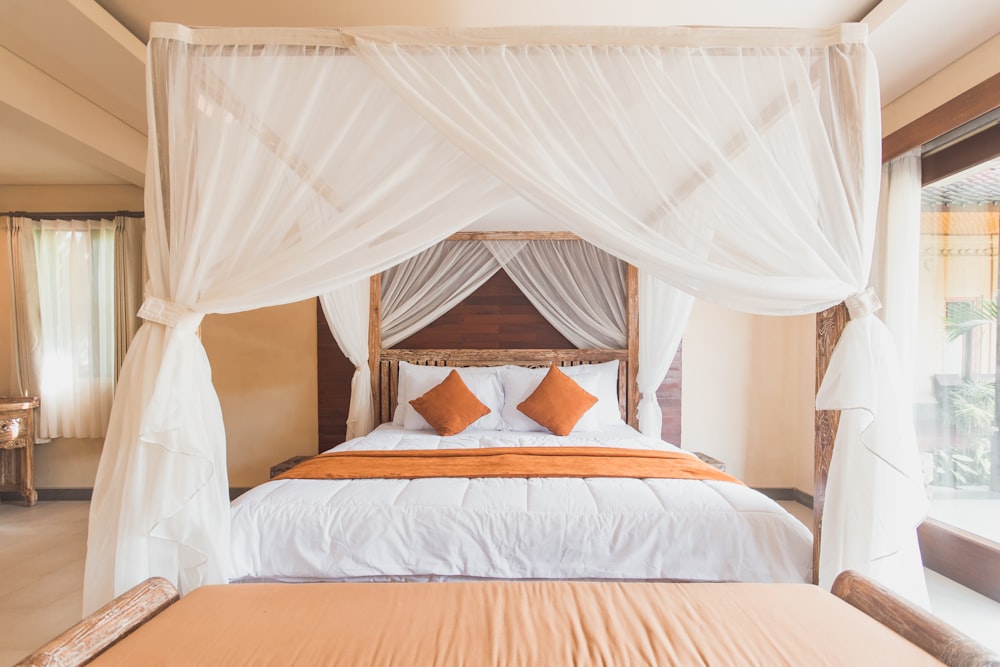 white mosquito net with brown wooden bed frame