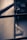 A close-up of a metal window latch attached to a weathered window frame. The image is composed in soft focus with a blurred background, giving a sense of depth. The lighting casts a subtle shadow on the frame, evoking a sense of nostalgia.