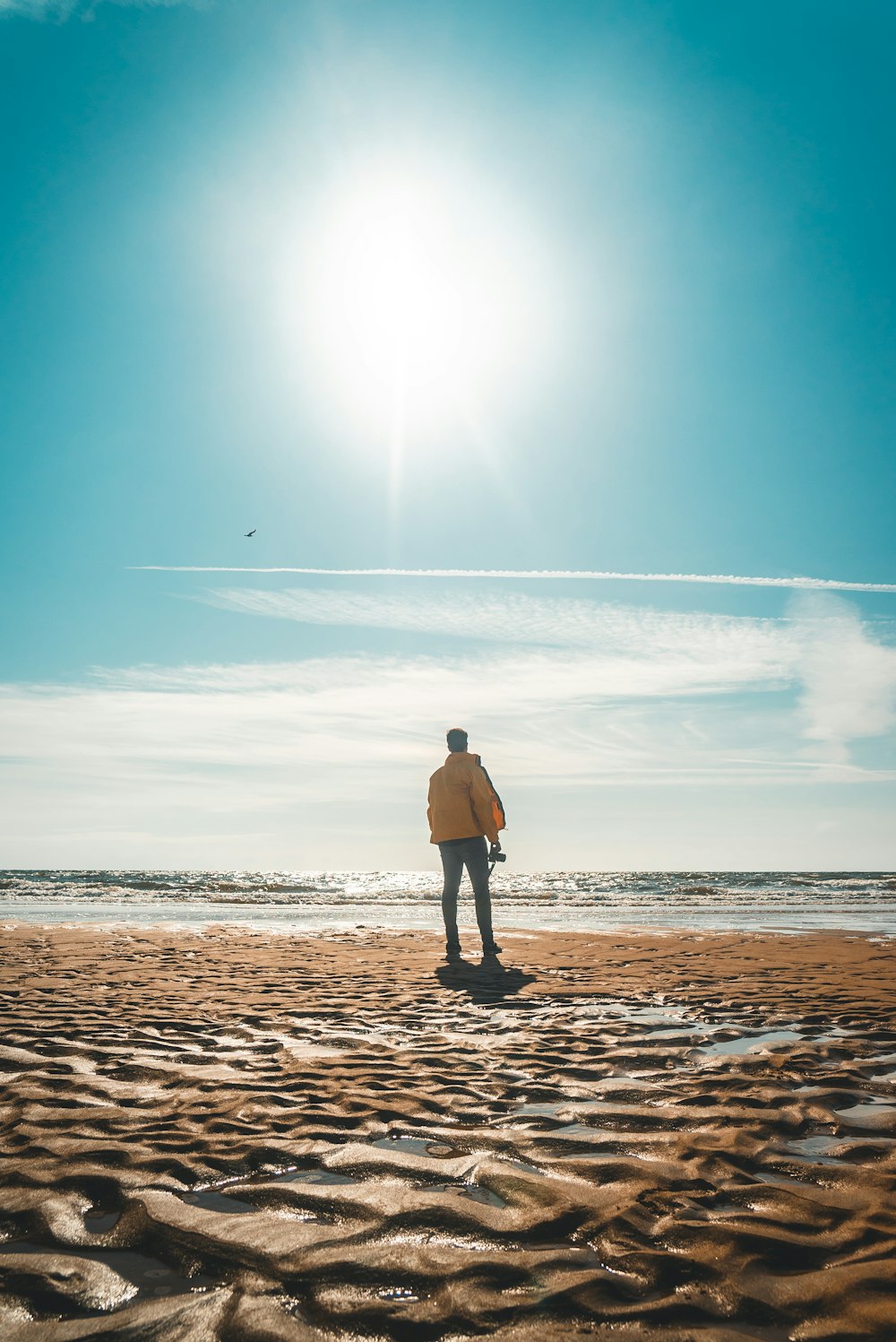 man in yellow jacket standing in front of shore