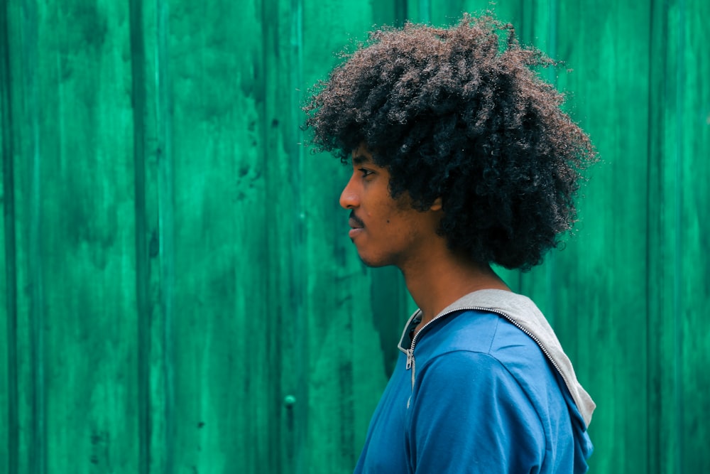 man facing right near green wall