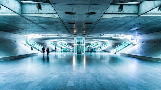 A sleek, futuristic office lobby with a person walking through an automatic door, highlighted by subtle blue and white tech overlays.