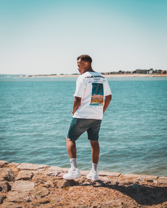 man standing on rock formation beside body of water in Portsmouth United Kingdom