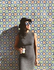 woman standing near the wall while holding beer bottle