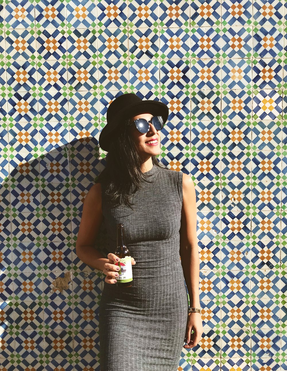 woman standing near the wall while holding beer bottle