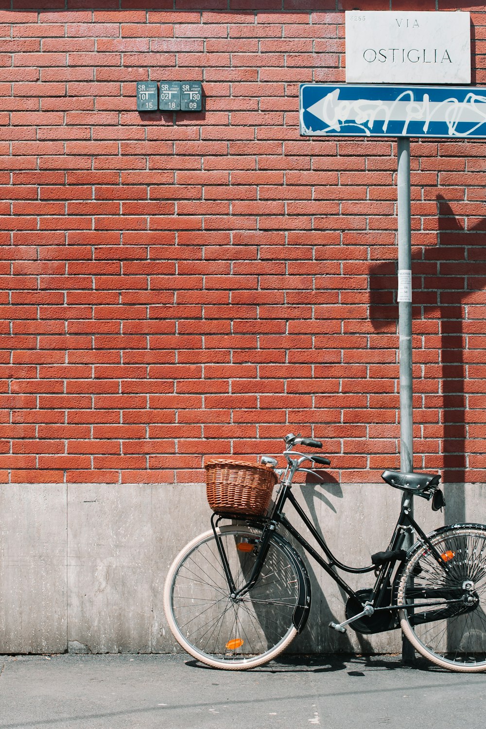 Schwarzes Cruiser-Fahrrad auf grauem Stahlpfosten angelehnt