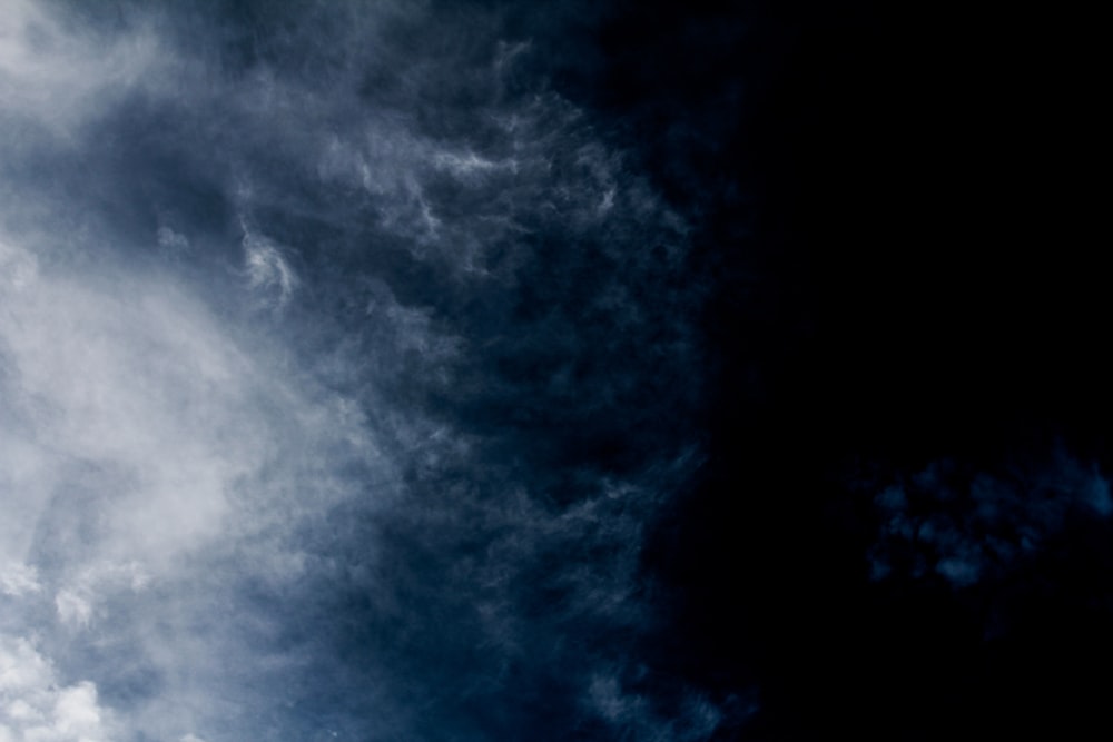 a plane flying through a cloudy blue sky