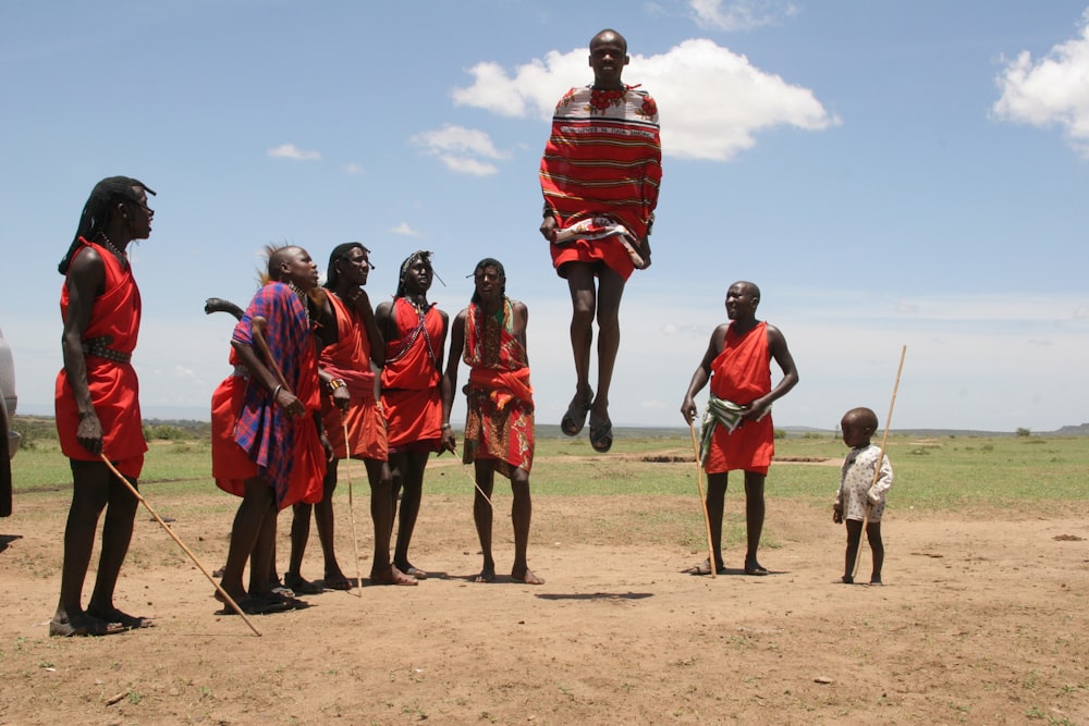 person in red dress jumping over brown soil