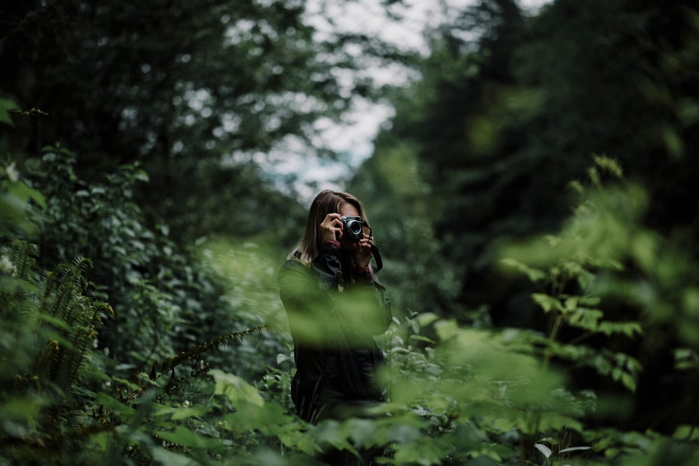 woman taking photo of trees