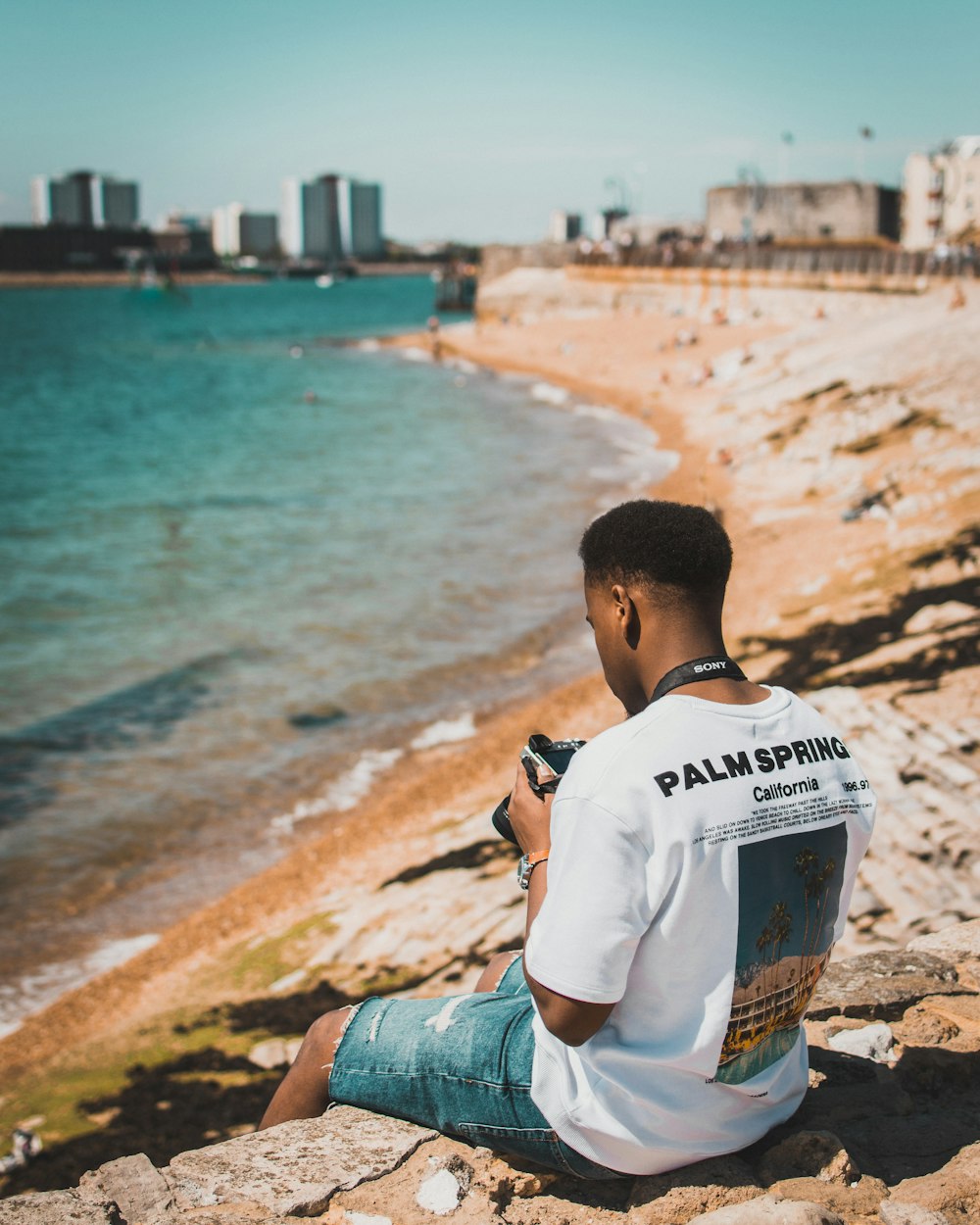 man sitting on rock near seashore