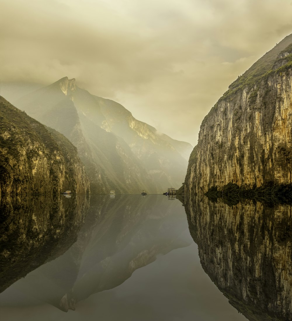 Acqua tra la montagna rocciosa sotto il cielo nuvoloso bianco durante la foto diurna