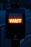 turned on black road signage displaying wait