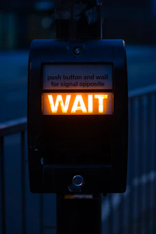 turned on black road signage displaying wait