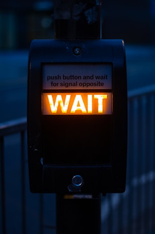 turned on black road signage displaying wait