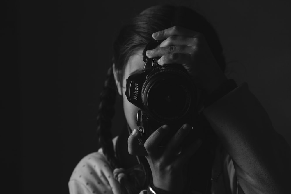 girl taking photo using Nikon DSLR camera in grayscale photography
