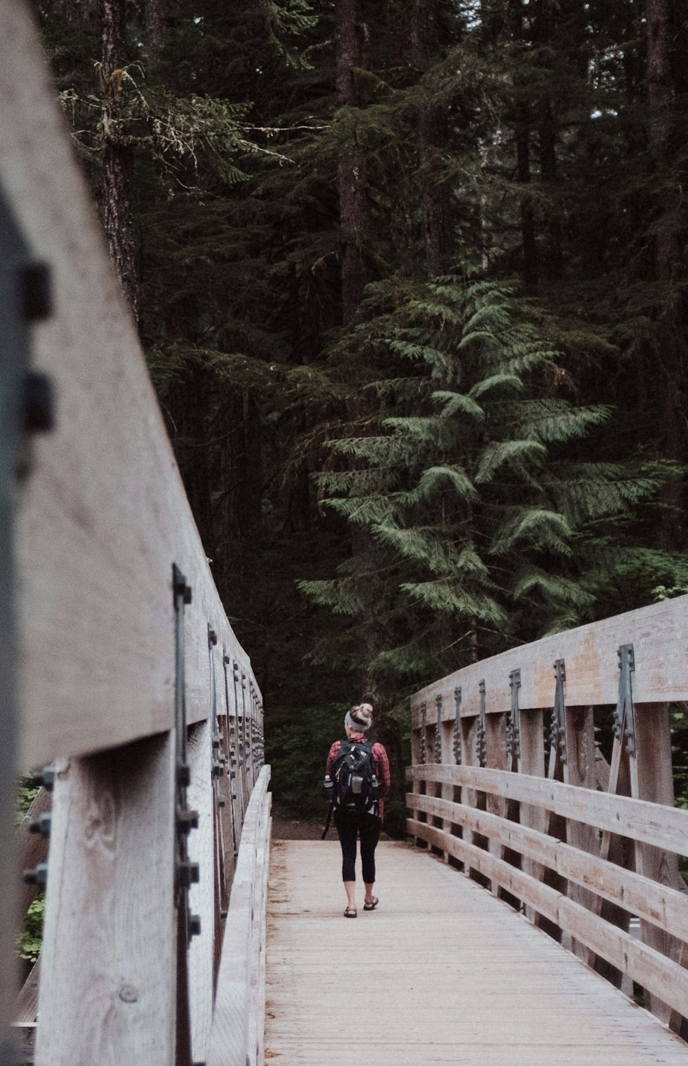 woman walking on brown wooden bridge