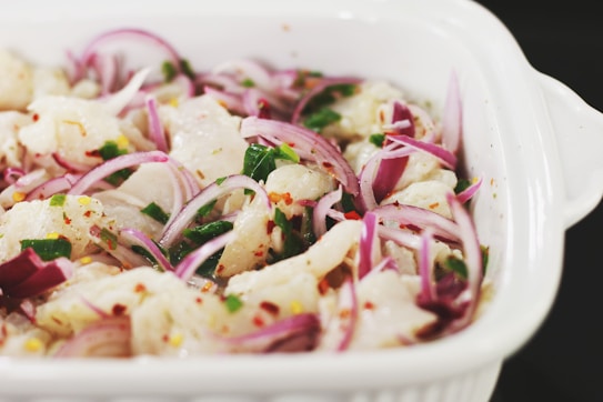 Ceviche peruano servido en cuenco de cerámica con cebolla morada y limón.