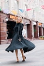 selective focus photo of smiling woman wearing black dress standing on concrete pavement