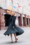 selective focus photo of smiling woman wearing black dress standing on concrete pavement