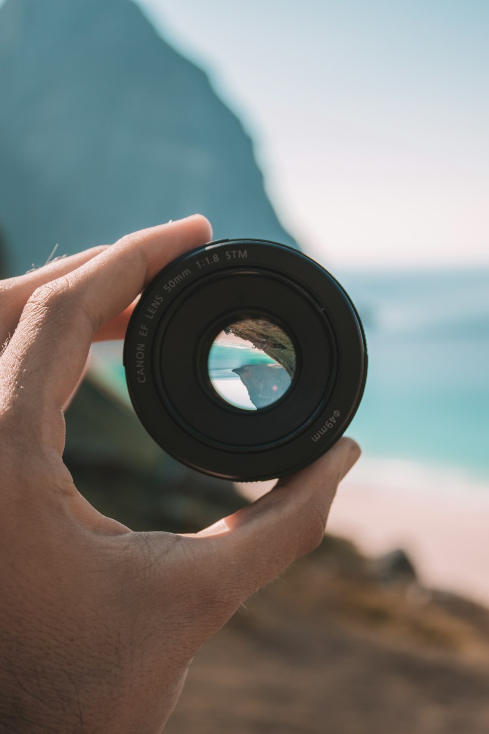 person holding 50 mm Canon EF lens