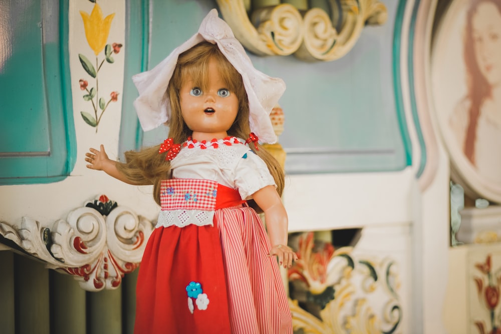 brown haired porcelain doll behind white and blue floral surface