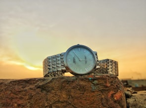 A stylish wrist wearing an exclusive, imported watch with a sunset background.