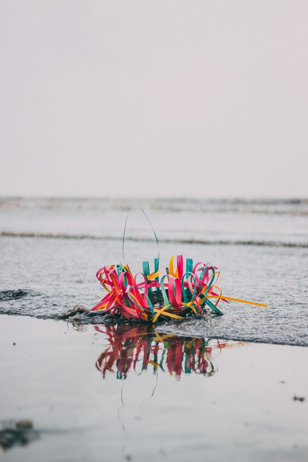 selective color photo of multicolored basket on shore