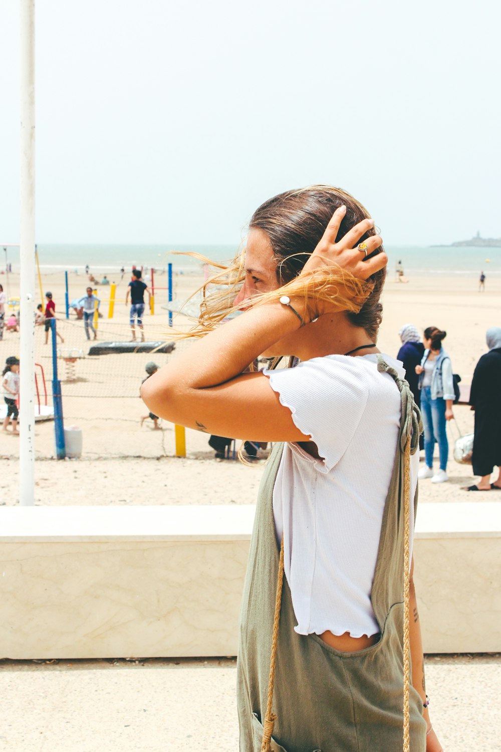 mujer en la playa con las manos en la cabeza