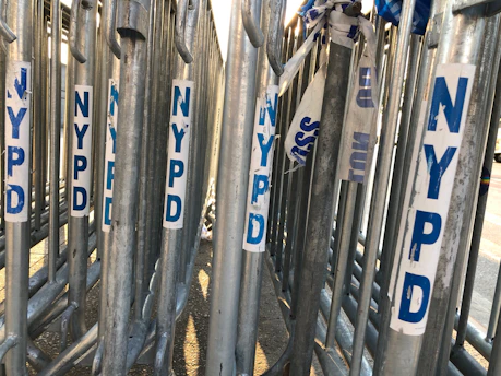 Steel crowd control barriers lined up securing a busy construction site under clear daylight.