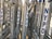Metal barricades with multiple NYPD stickers are arranged in close proximity. Blue and white tape is tied around some of the bars. The scene is illuminated by warm sunlight.