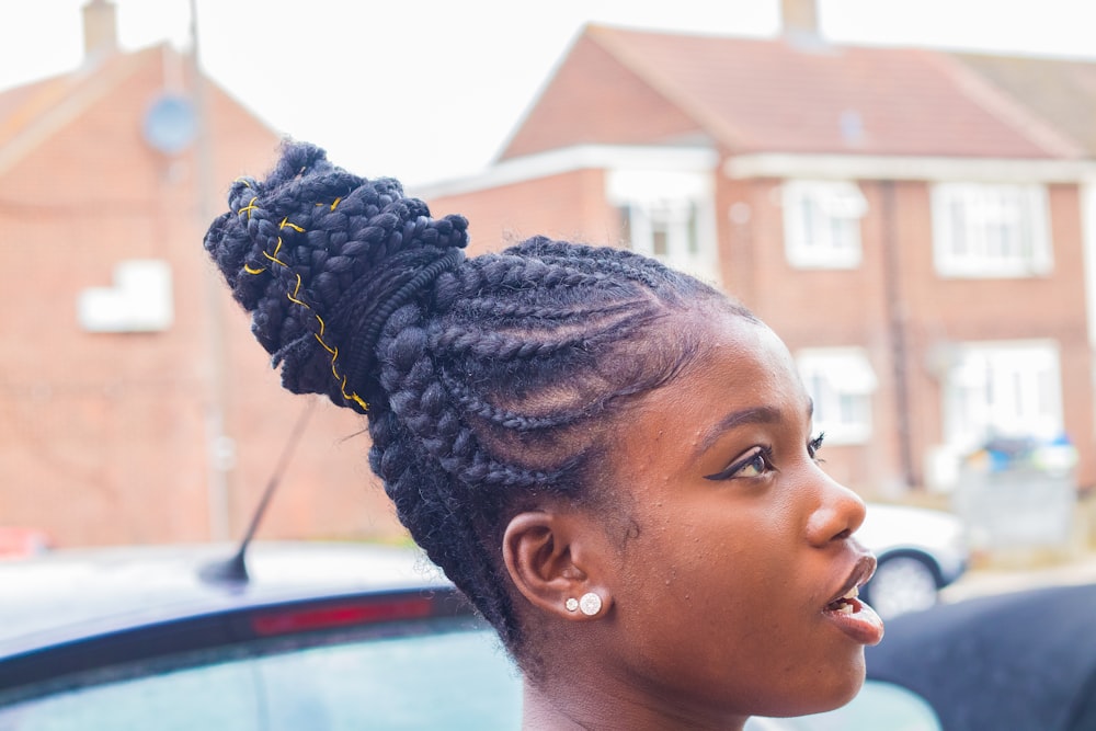 woman with braided hair standing near car