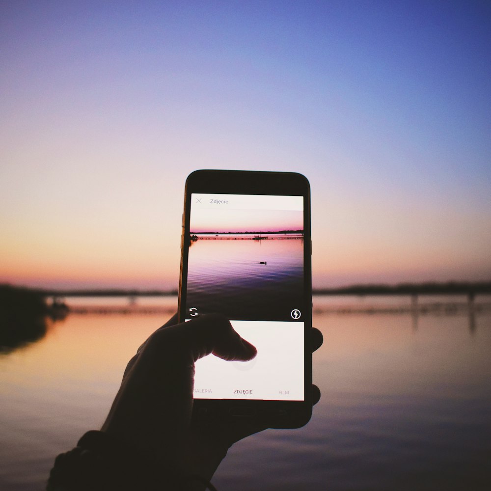 person holding turned-on smartphone taking photo