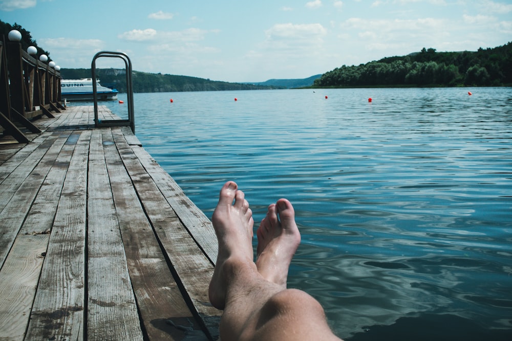 Person, die auf braunem Holzboden in der Nähe des Pools sitzt