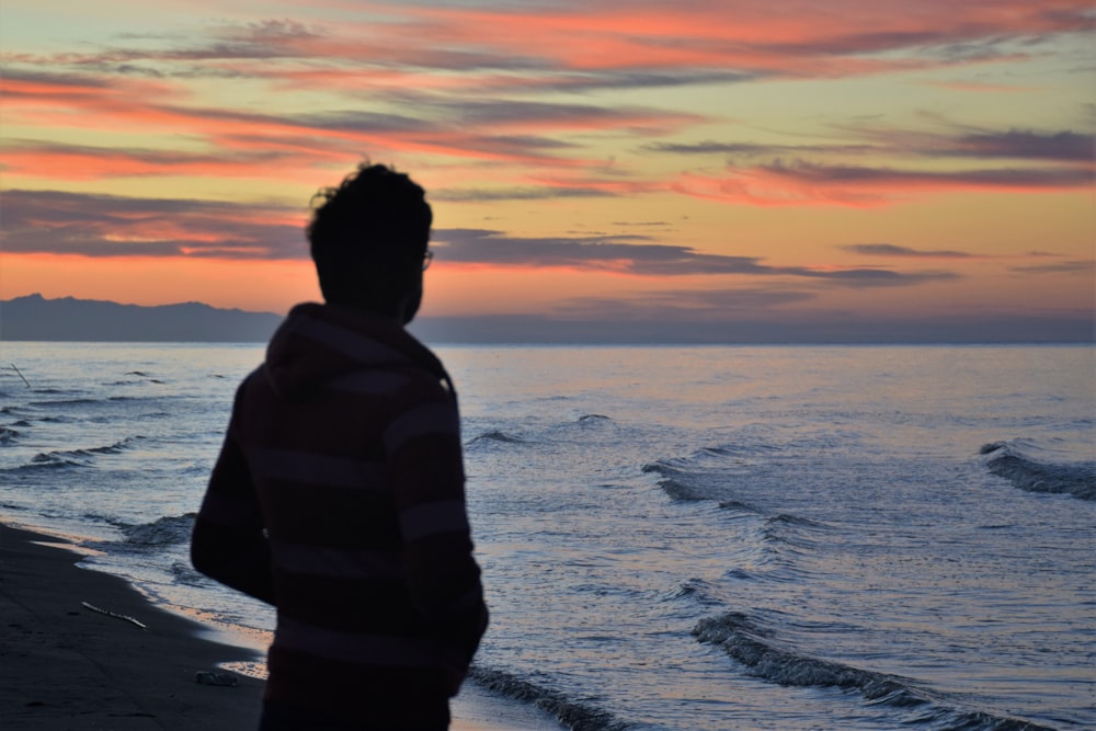 hombre de pie frente a la orilla del mar