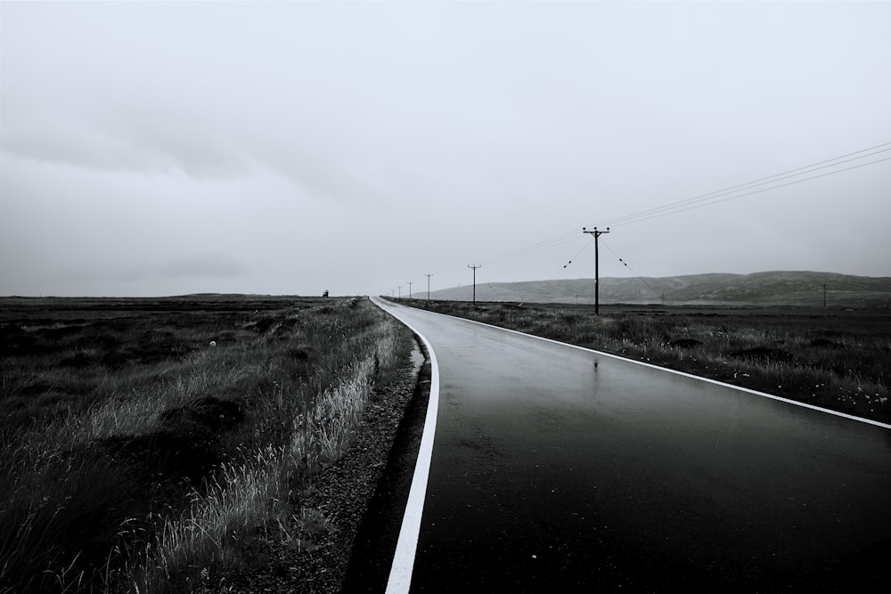 gray concrete road near mountain under white clouds at daytime