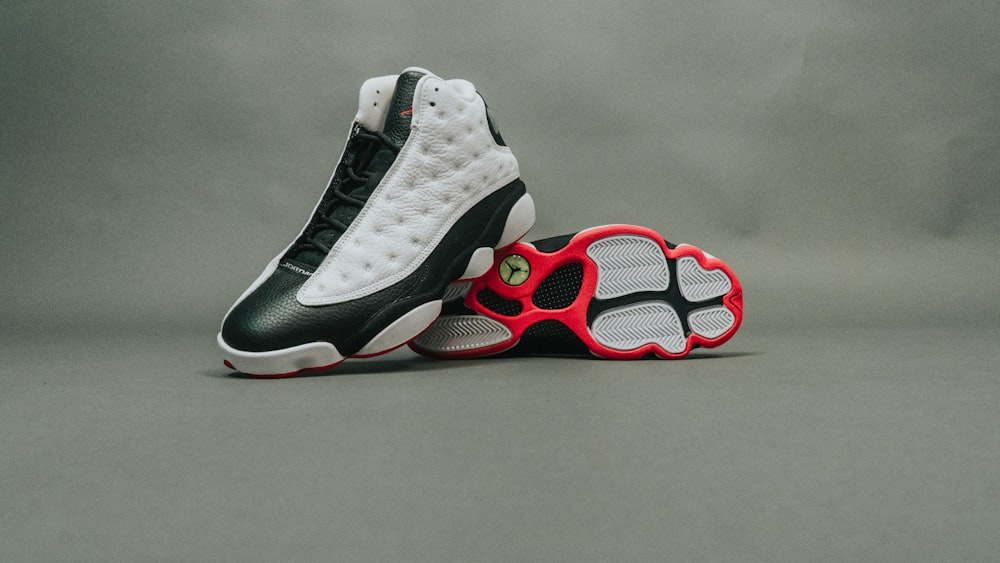 Paar schwarz-weiße Air Jordan 13 Schuhe auf grauem Untergrund