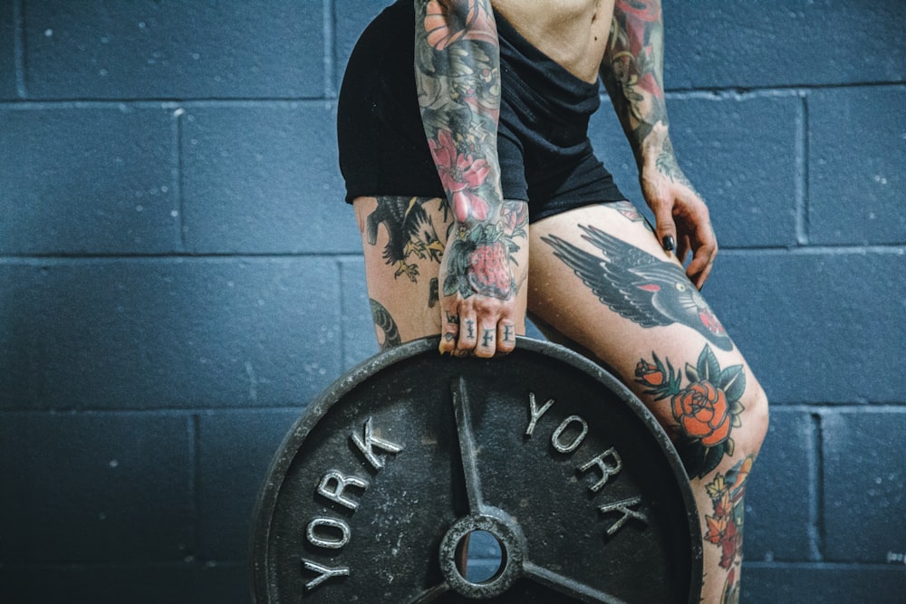 person carrying black weight plate with right hand