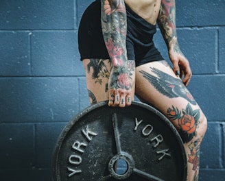 person carrying black weight plate with right hand