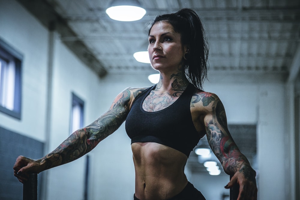 femme portant un soutien-gorge de sport noir avec des tatouages