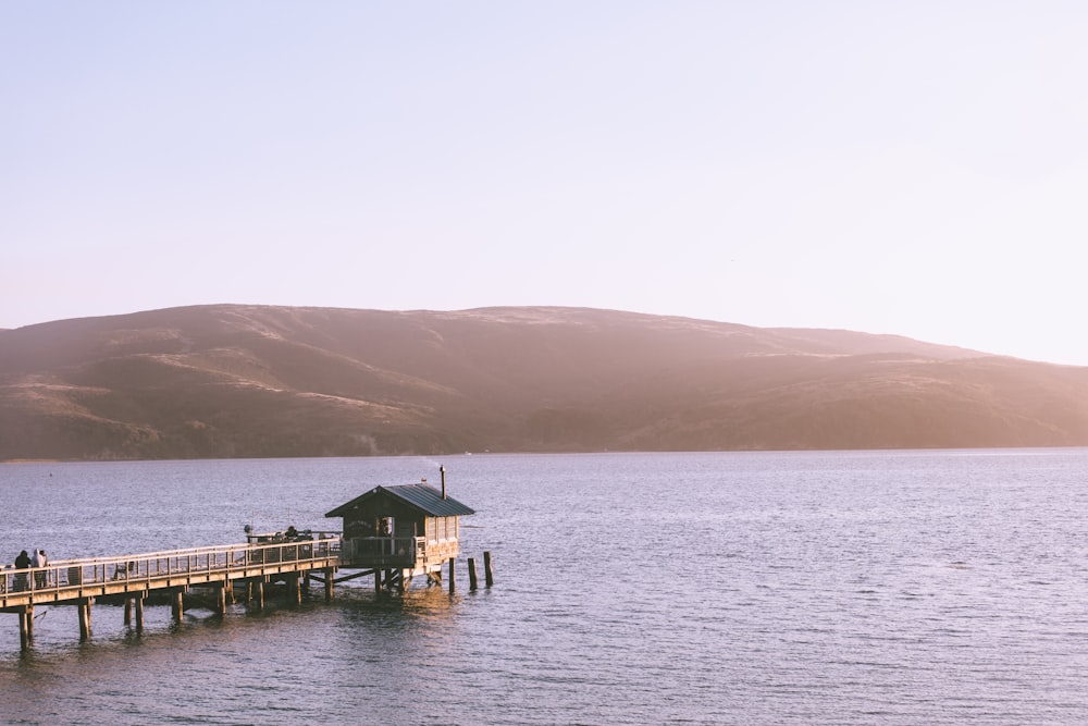 Pontile di legno che va al cottage sopra lo specchio d'acqua vicino alla montagna