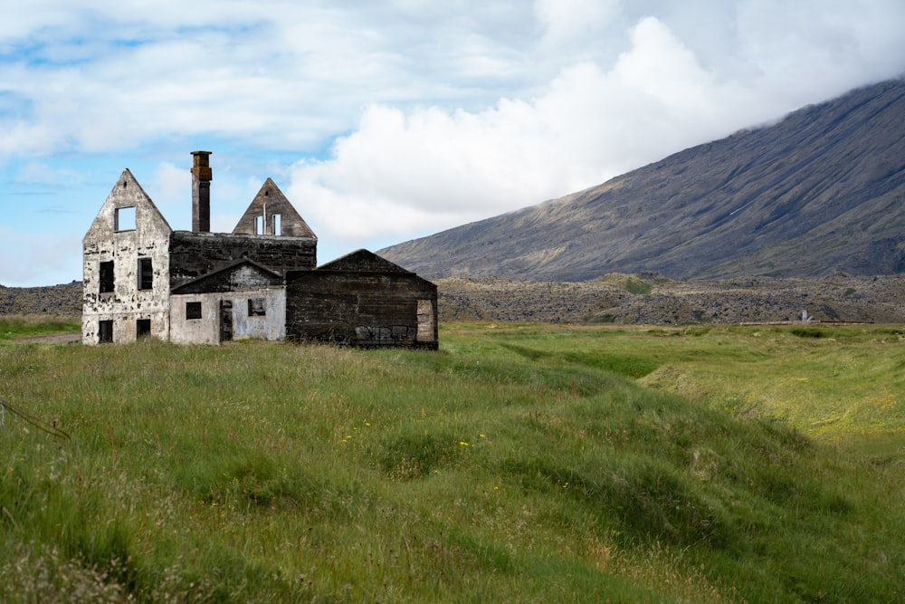 gray building near grass field and mountain under white cloud blue skies