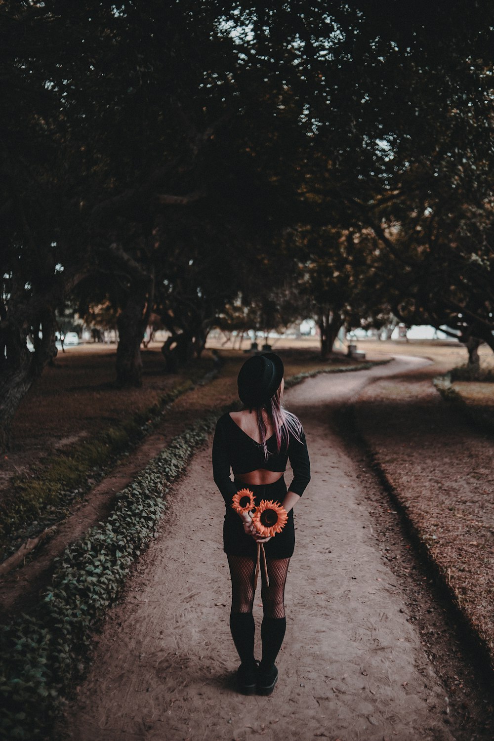 Mujer que camina en el parque sosteniendo la flor durante el día